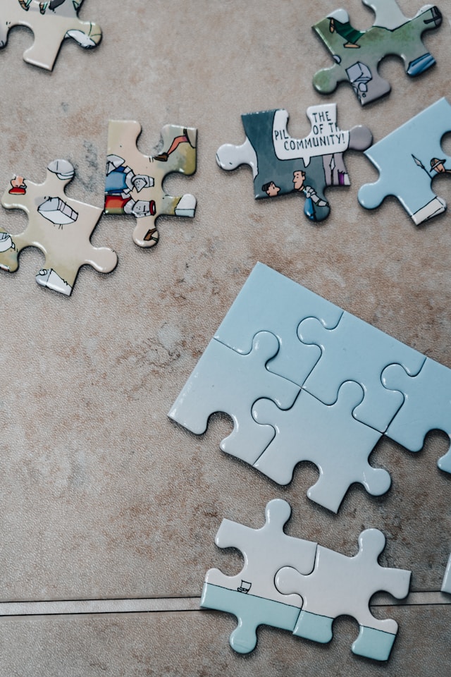White jigsaw puzzle pieces on brown marble table. Photo credit - Jonny Gios - Unsplash